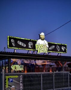 Podświetlany duży baner reklamowy firmy gastronomicznej montowany na dachu.